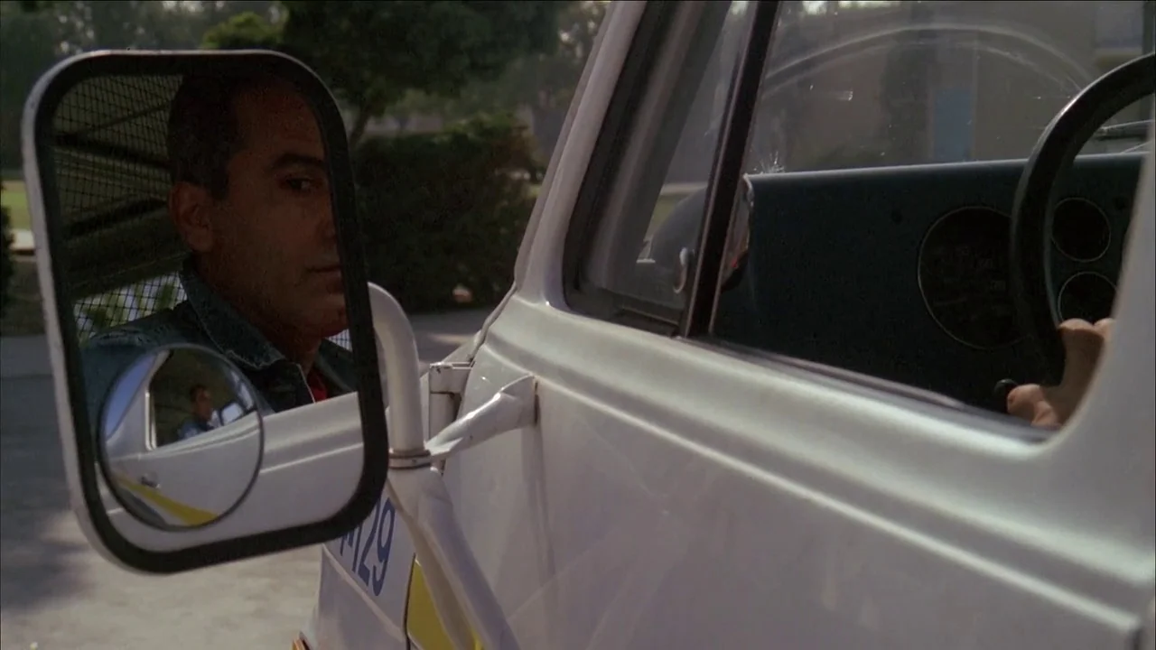 The Slumber Party Massacre (1982) movie still: medium — The exterior of a white utility truck features a large square side-view mirror. A man is…