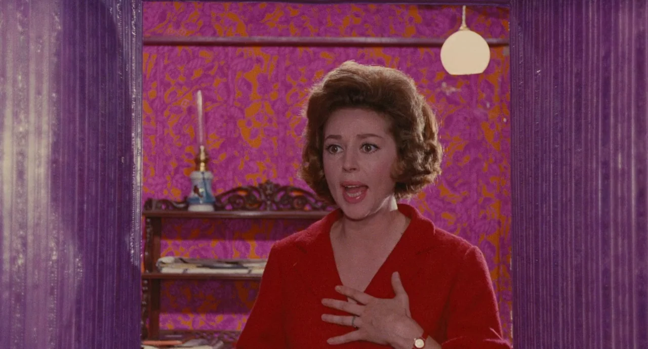 The Umbrellas Of Cherbourg (1964) movie still: medium — A room features vibrant magenta and orange patterned floral wallpaper and deep purple…