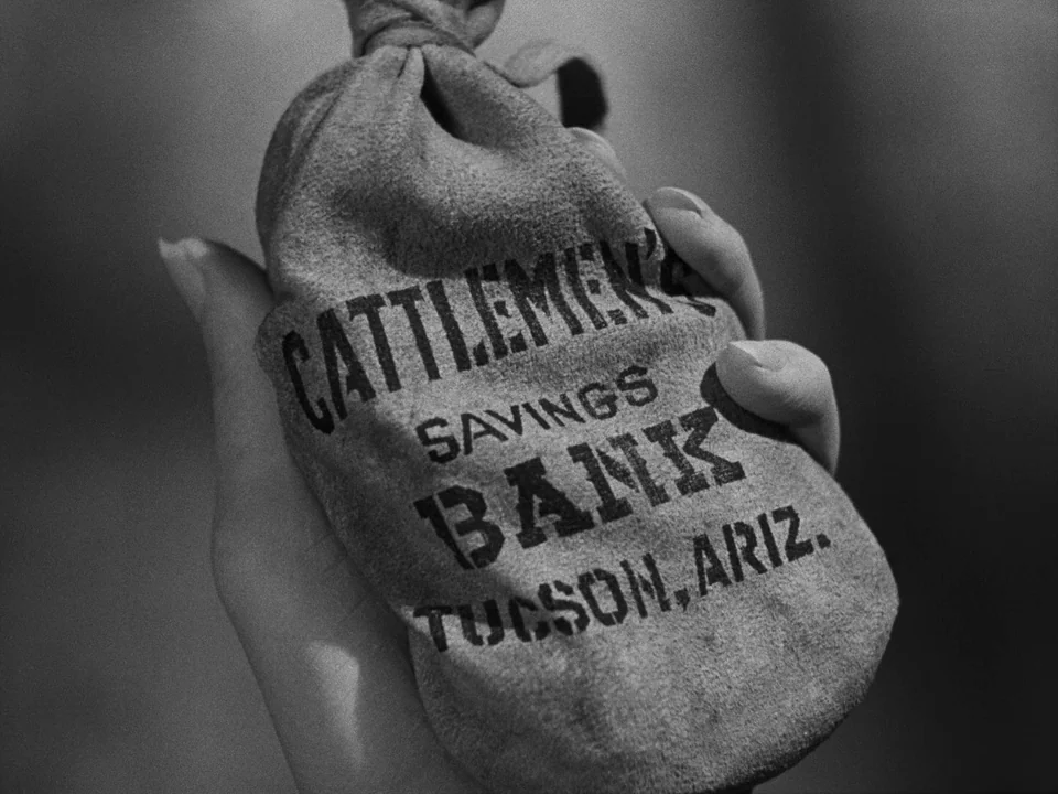 My Darling Clementine (1946) movie still: closeup — A close-up of a small, textured fabric money bag held by a human hand. The bag has printed text…