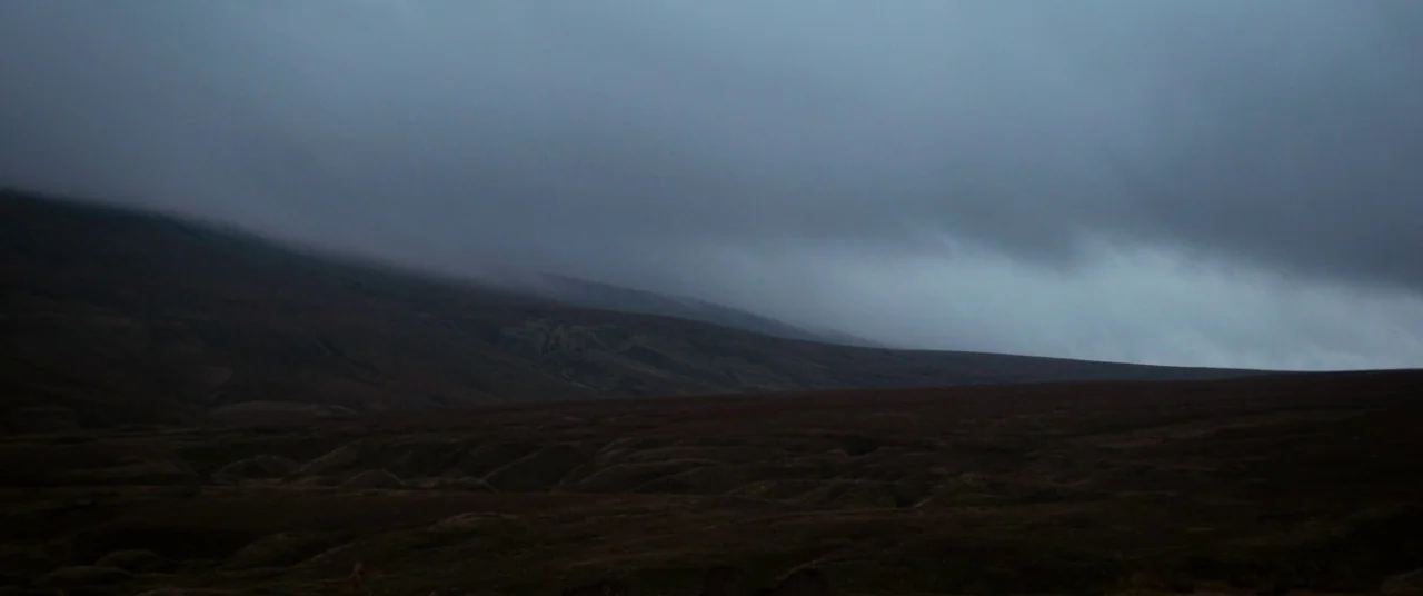 Lady Macbeth (2016) movie still: establishing — An expansive, undulating moorland landscape stretches under a thick, low-hanging overcast sky. Heavy…