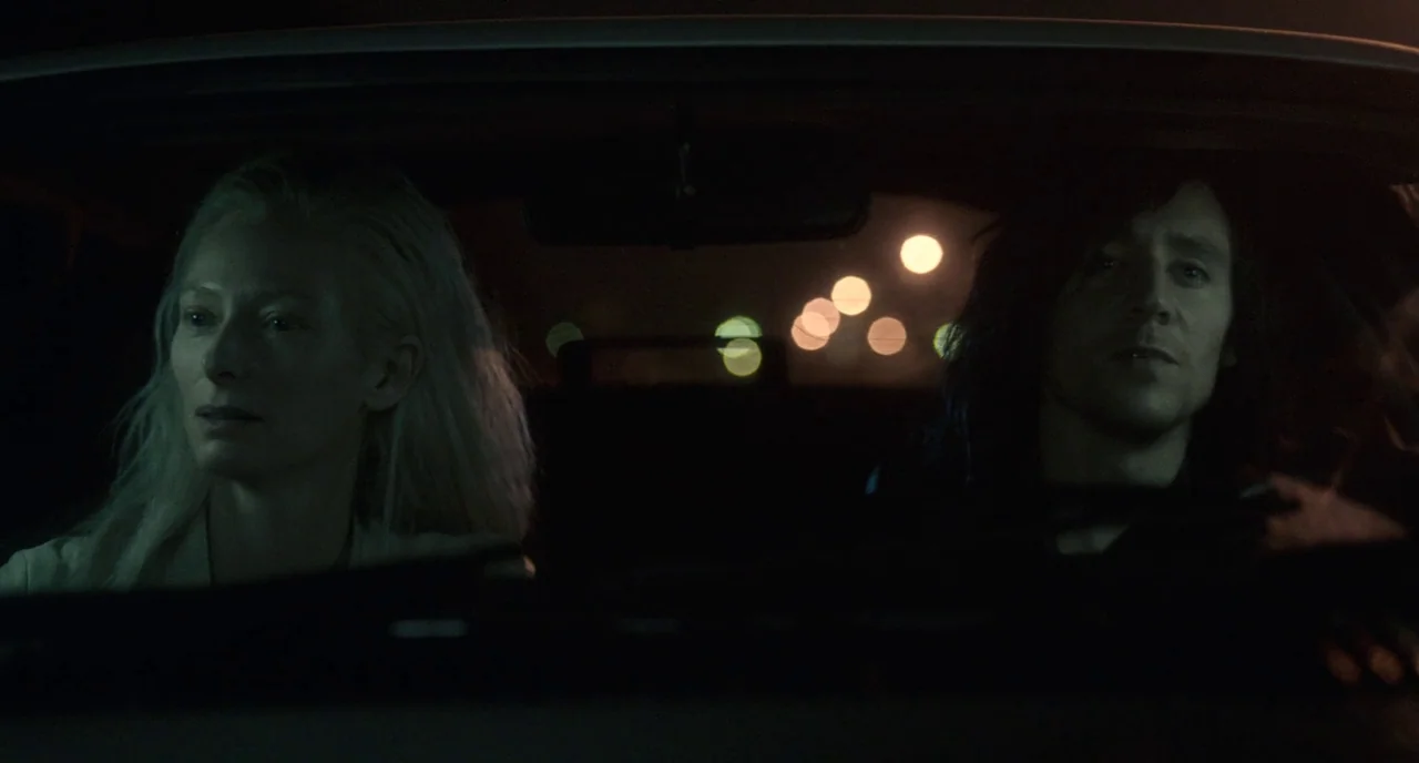 Only Lovers Left Alive (2013) movie still: medium — The interior of a car at night with two occupants sitting in the front seats. Blurred…