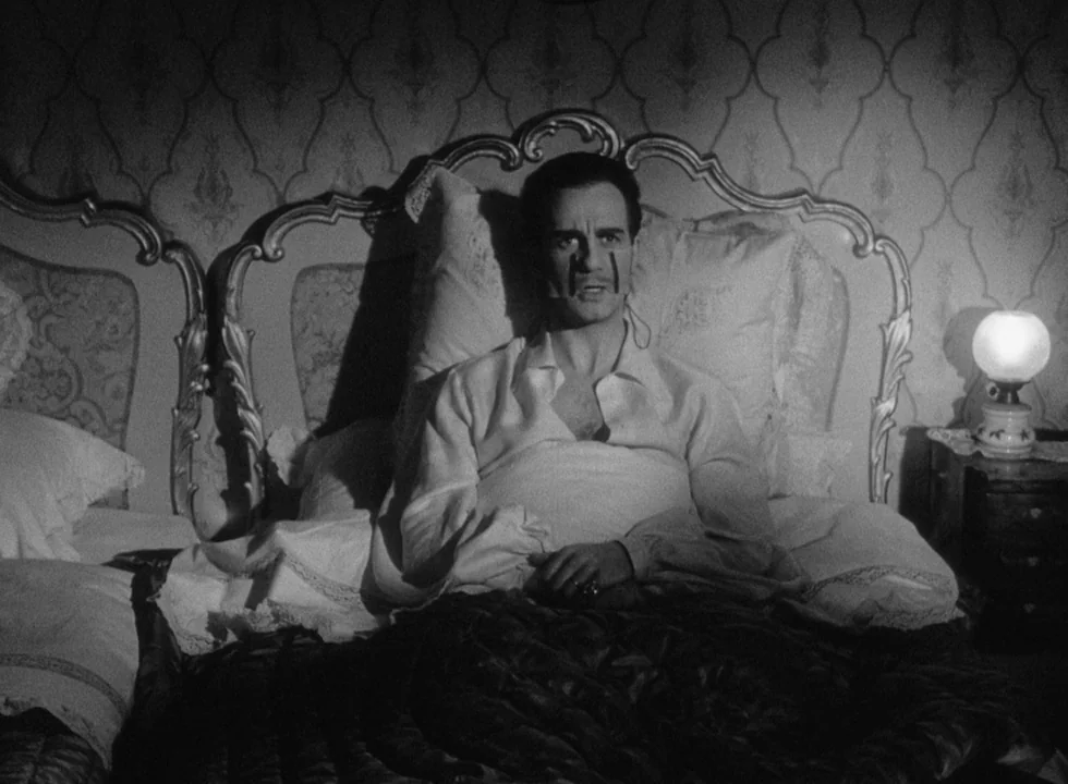 Smiles Of A Summer Night (1955) movie still: medium — A man sits upright against a large ornate headboard covered by patterned damask wallpaper. The…