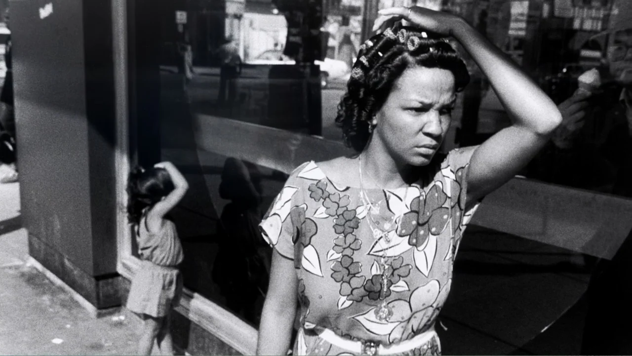 Mary J. Blige's My Life (2021) movie still: medium — A city street exterior features a large glass storefront window reflecting the surroundings. A…