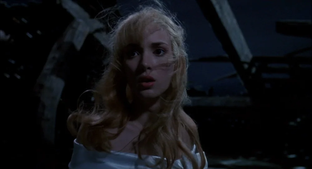 Edward Scissorhands (1990) movie still: medium — A dark, ruined interior features weathered wooden beams and deep shadows in the background. A young…