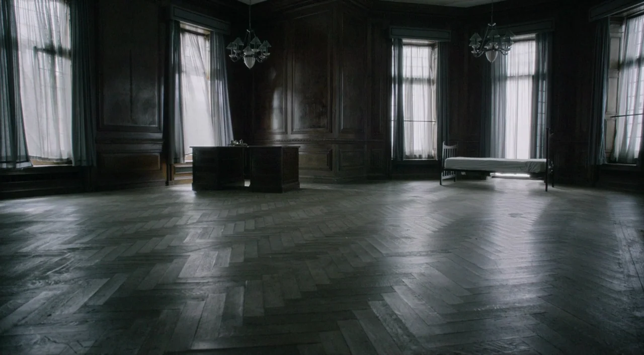 The Death of Stalin (2017) movie still: establishing — A spacious room features dark wood-paneled walls and a worn herringbone wooden floor. A lone…