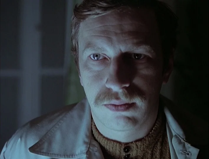 Camera Buff (1979) movie still: closeup — A man stands in a dark room with his face illuminated from below. He stares forward, his features…
