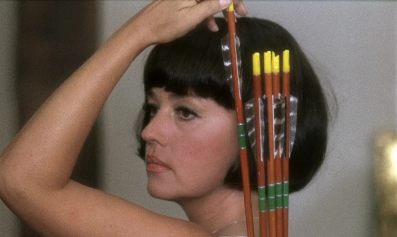 The Bride Wore Black (1968) movie still: closeup — A woman stands in a nondescript indoor space with a neutral wall behind her. She holds a small…