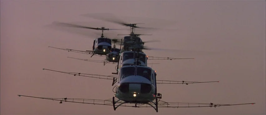 Short Cuts (1993) movie still: wide — A formation of military helicopters flies through a hazy twilight sky. The helicopters are arranged in a…