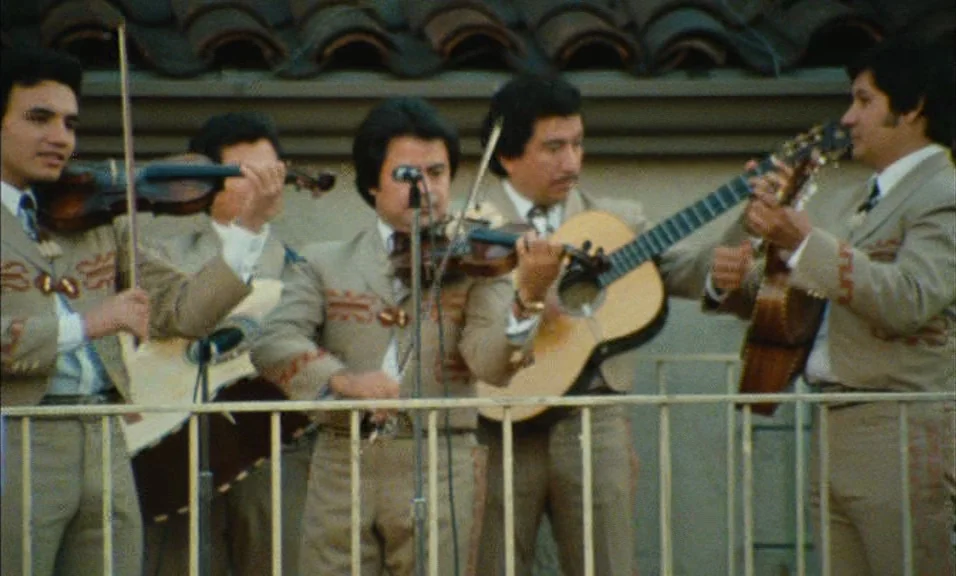 Documenteur (1981) movie still: medium — Four musicians perform on a balcony behind a white metal railing. The men wear matching tan charro suits…