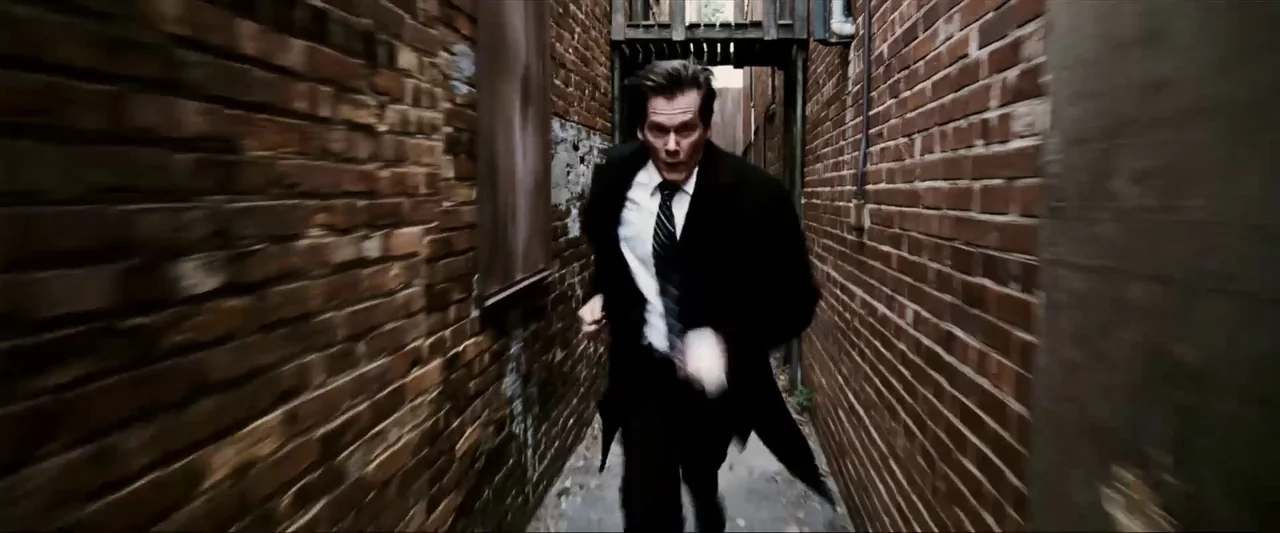Death Sentence (2007) movie still: medium — A narrow corridor flanked by high, weathered red brick walls on both sides. A man in a dark suit runs…