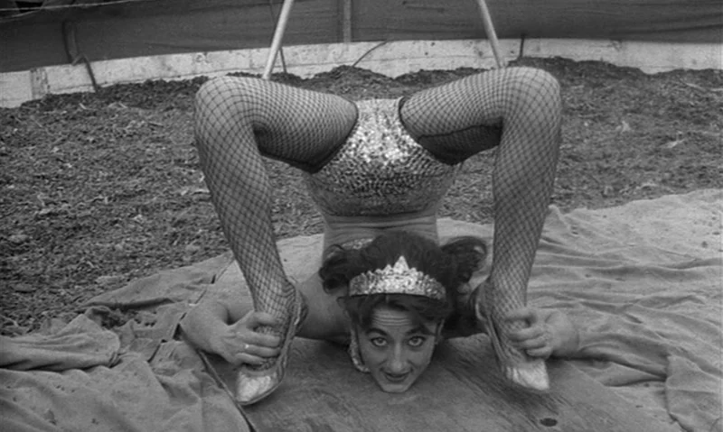 Man Is Not Bird (1965) movie still: medium — A circus tent floor covered in dirt and tan fabric serves as the surface. A female performer in…