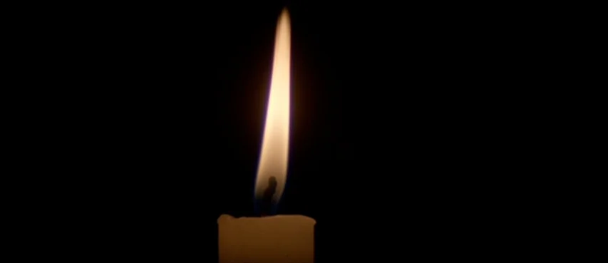 The Thin Red Line movie still: closeup — A single lit white candle stands against a completely black void. The flame flickers upward with a bright…