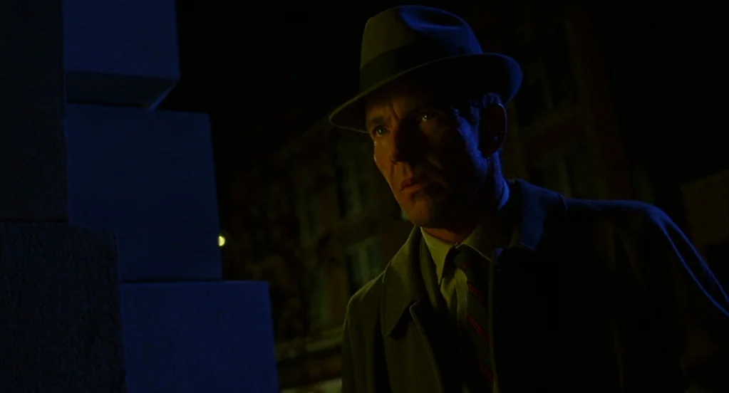 Far From Heaven (2002) movie still: medium — A man in a fedora stands on a dark city street at night. He is illuminated by a streetlamp from above…