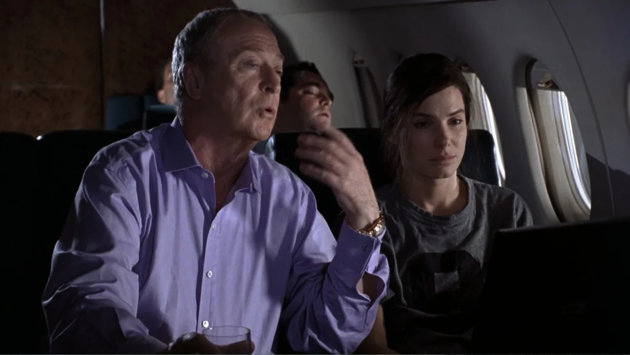 Miss Congeniality (2000) movie still: medium — A private airplane cabin features leather seats and small passenger windows. An older man speaks to a…