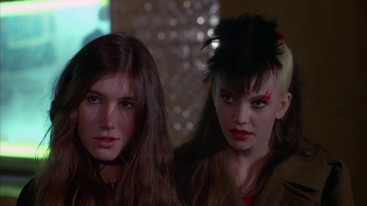 Ladies and Gentlemen, the Fabulous Stains (1985) movie still: medium — A dark indoor space featuring a blurred green glowing sign in the background.…