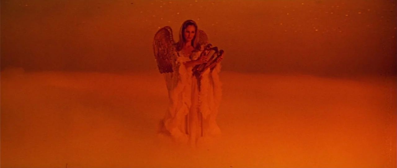Casino Royale (1967) (1967) movie still: fullbody — A woman dressed as an angel stands in the middle of dense orange clouds. The subject holds a…