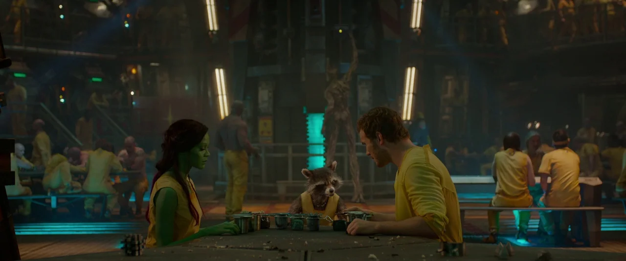 Guardians of the Galaxy (2014) movie still: wide — A dark industrial cafeteria with glowing cyan floor strips and yellow-clad inmates seated.
