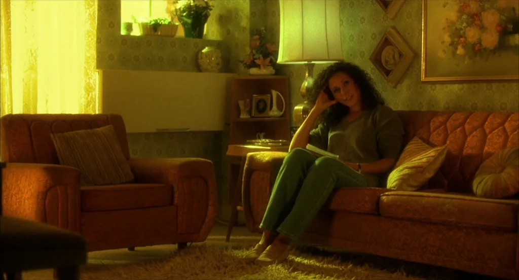 He Got Game (1998) movie still: medium — A 1970s style space with patterned wallpaper, a floral painting, and vintage furniture. A woman with long…