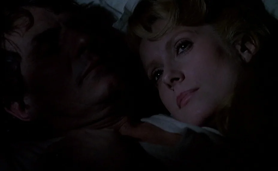 The Last Metro (1980) movie still: closeup — A dark bedroom with white linens visible beneath the subjects. A man and a woman lie in bed in close…