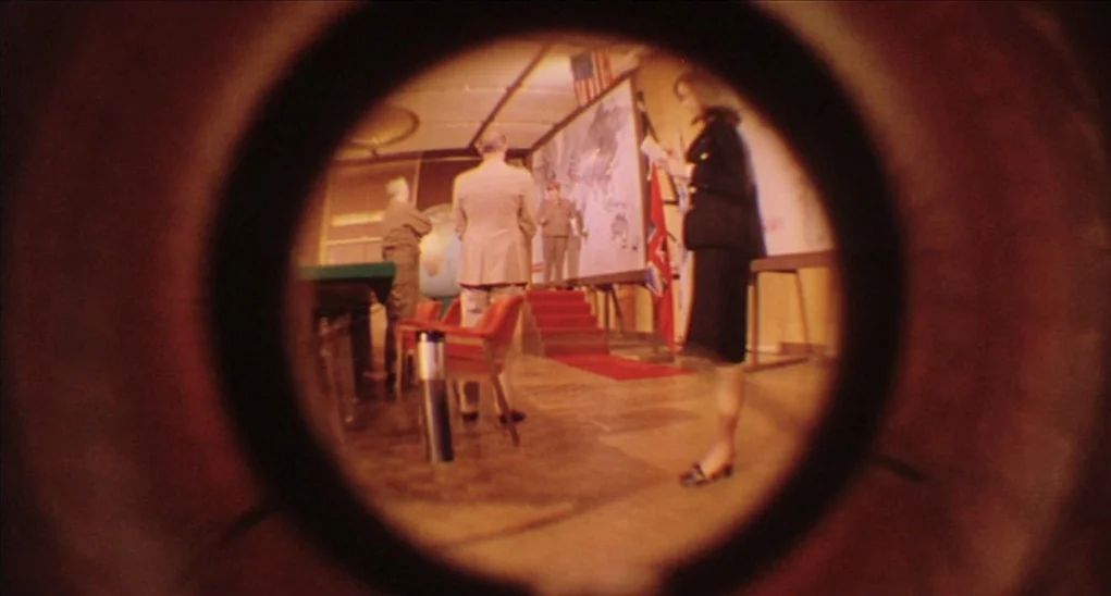 Dr. Goldfoot and the Girl Bombs (1966) movie still: wide — A low-ceilinged room features a large wall-mounted map and several men standing nearby. A…