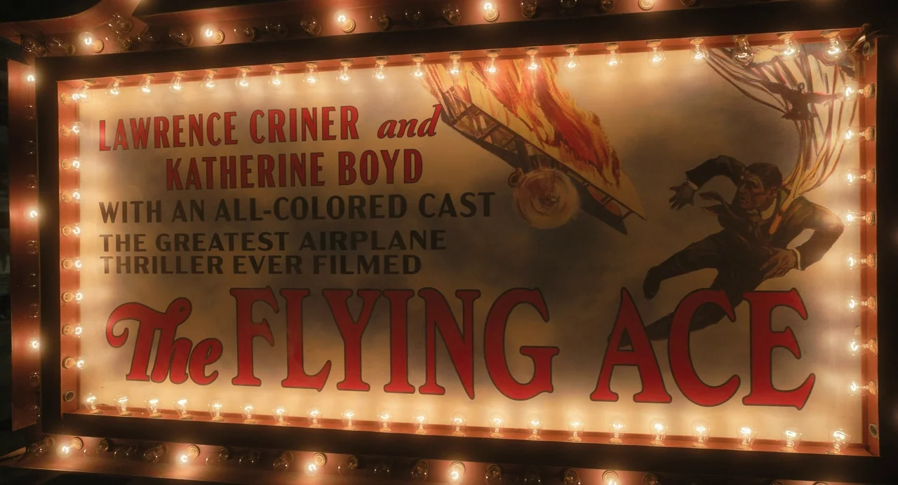 The Color Purple (2023) movie still: closeup — A vintage movie theater marquee displays a promotional poster for the film The Flying Ace. The poster…