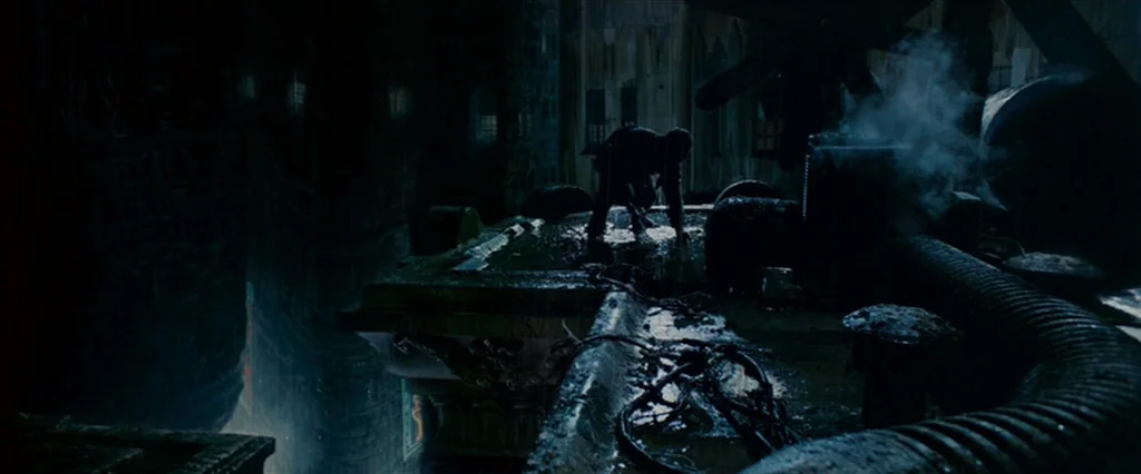 Blade Runner (1982) movie still: wide — A dark, rain-slicked building ledge overlooks a sprawling, industrial cityscape at night. A solitary figure…
