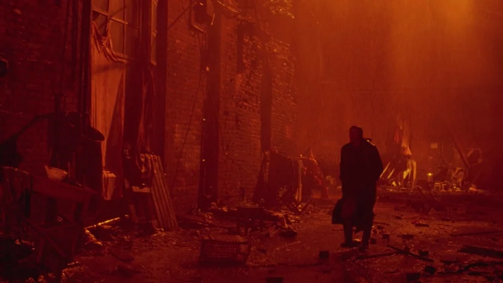 The Ugly Swans (2006) movie still: wide — A desolate urban space covered in scattered debris and wreckage from a collapsed building. A lone man…