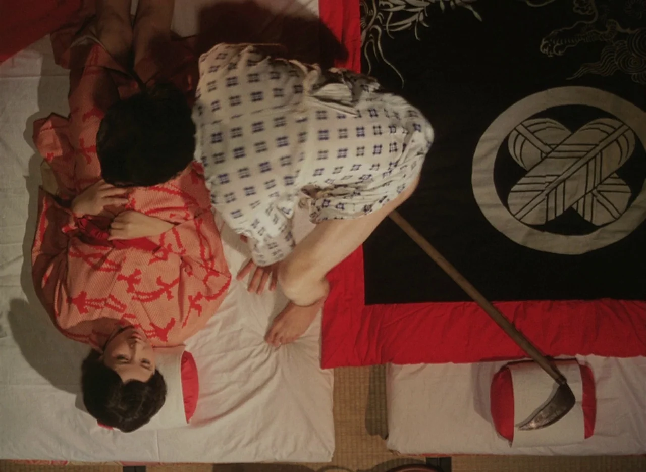 Pastoral To Die In The Country (1974) movie still: medium — Two individuals lie on traditional floor bedding atop a straw mat floor. A curved metal…