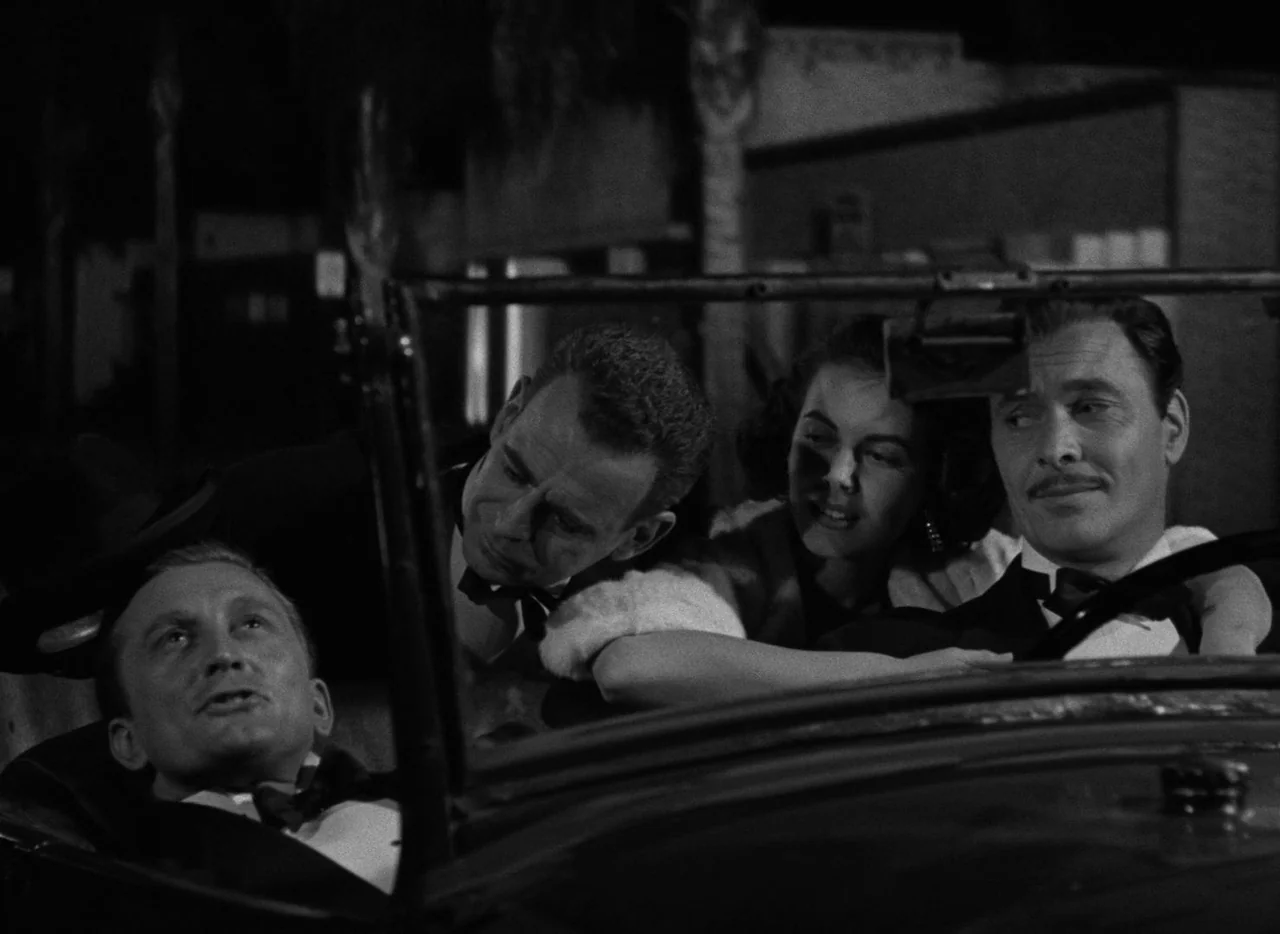 The Bad and the Beautiful (1952) movie still: medium — A group of four adults sits closely together inside an open-top convertible at night. The…