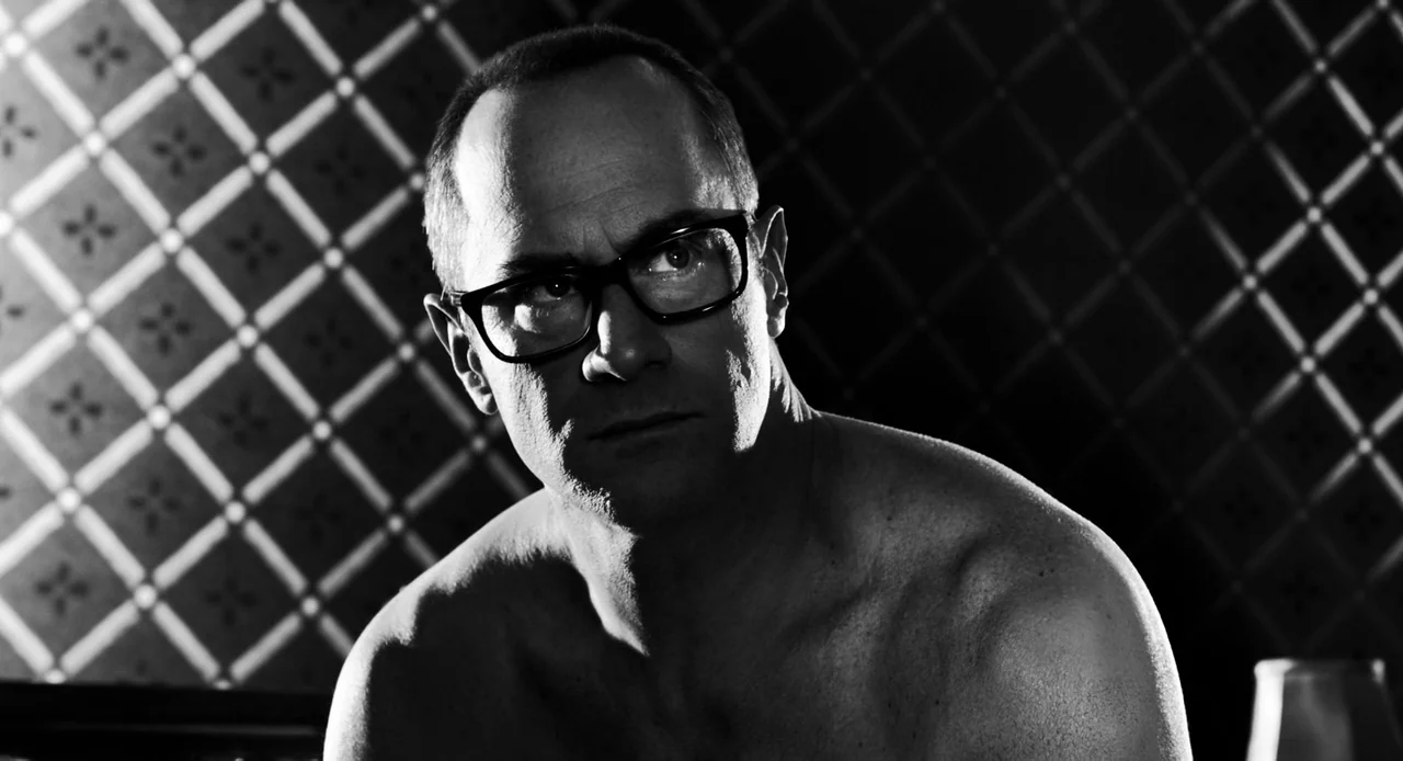 Sin City: A Dame to Kill For (2014) movie still: closeup — A high-contrast interior space featuring a patterned wallpaper backdrop behind a…