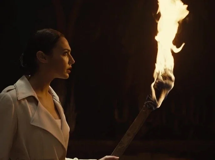 Zack Snyder's Justice League (2021) movie still: medium — A dark, undefined interior space is shrouded in deep shadow. A woman in a light-colored…