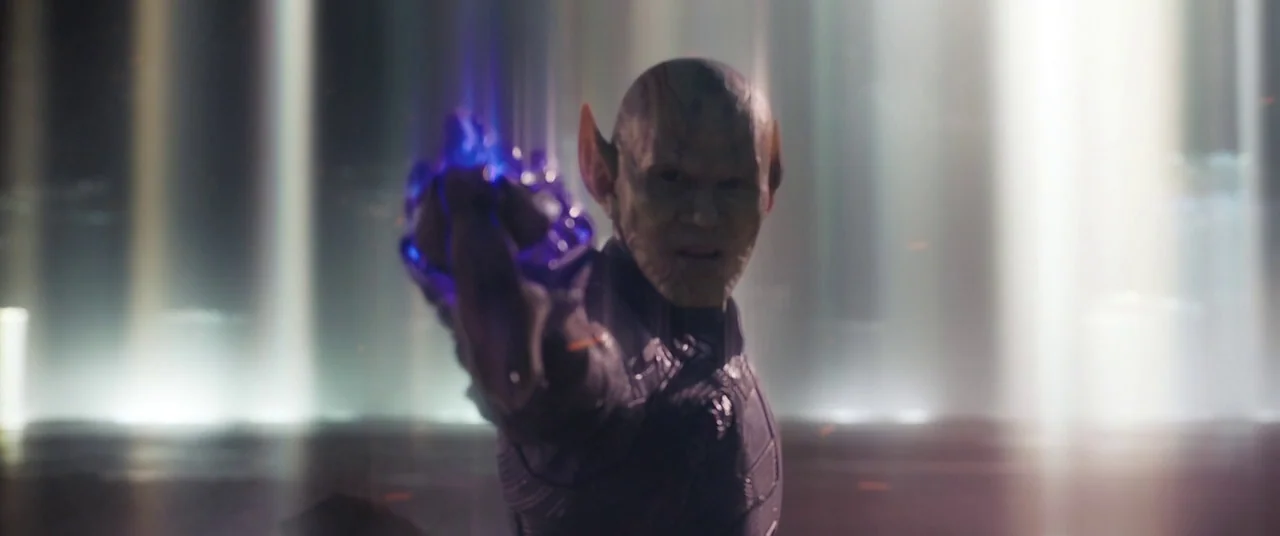Captain Marvel (2019) movie still: medium — A dark space characterized by glowing vertical streaks of light in the distant background. A humanoid…