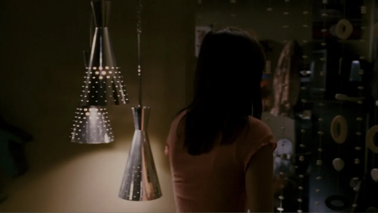 When a Stranger Calls (2006) movie still: medium — A dimly lit interior space features modern metallic pendant lighting fixtures. A woman stands…