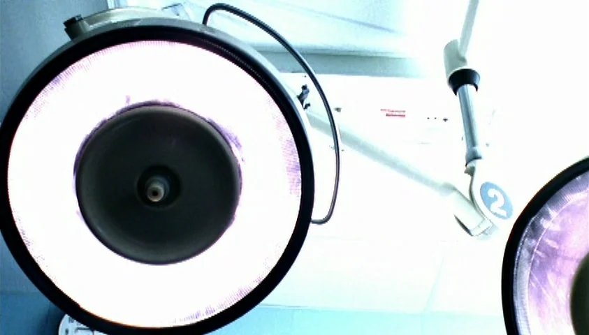 Maelström (2000) movie still: closeup — A high-intensity surgical lamp is suspended from a white ceiling track system. The light fixture is angled…