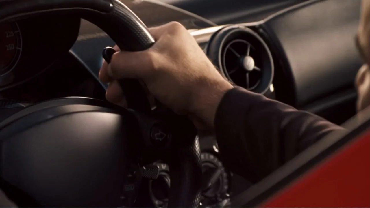 Redline (2007) movie still: closeup — The interior of a vehicle highlights the steering wheel and a driver hand. A hand grips the steering wheel…