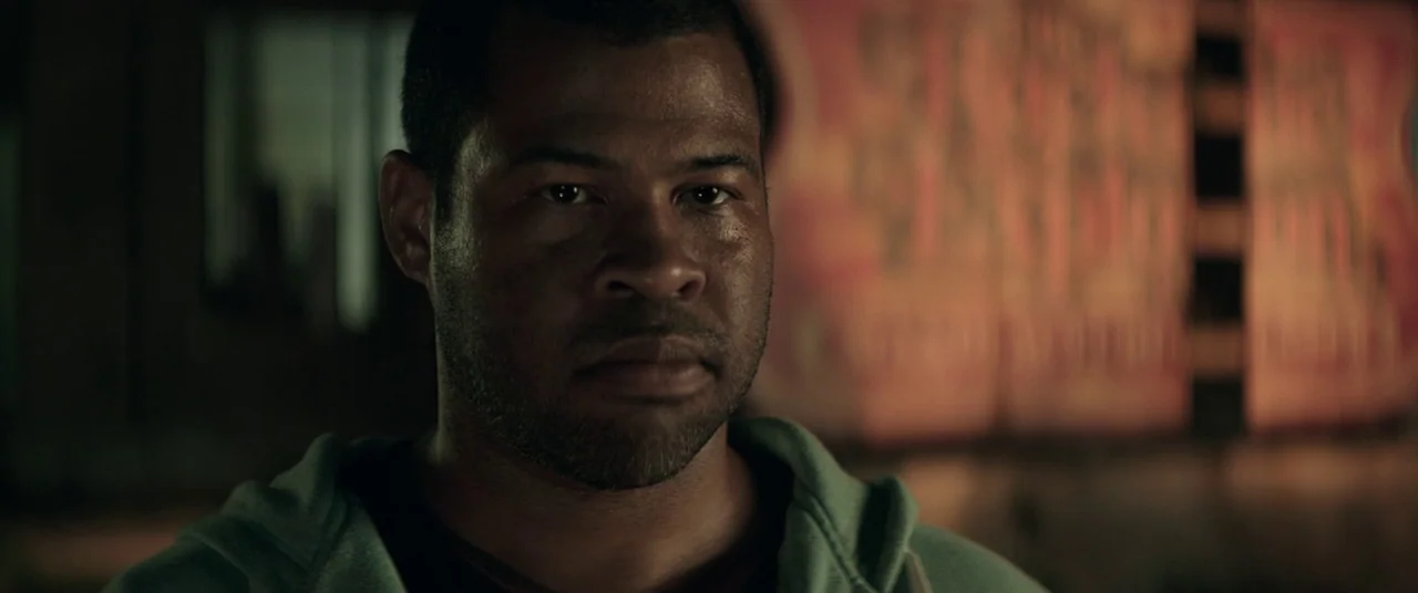 Keanu (2016) movie still: closeup — A dark urban street at night provides a blurred, indistinct industrial background behind the subject. A…