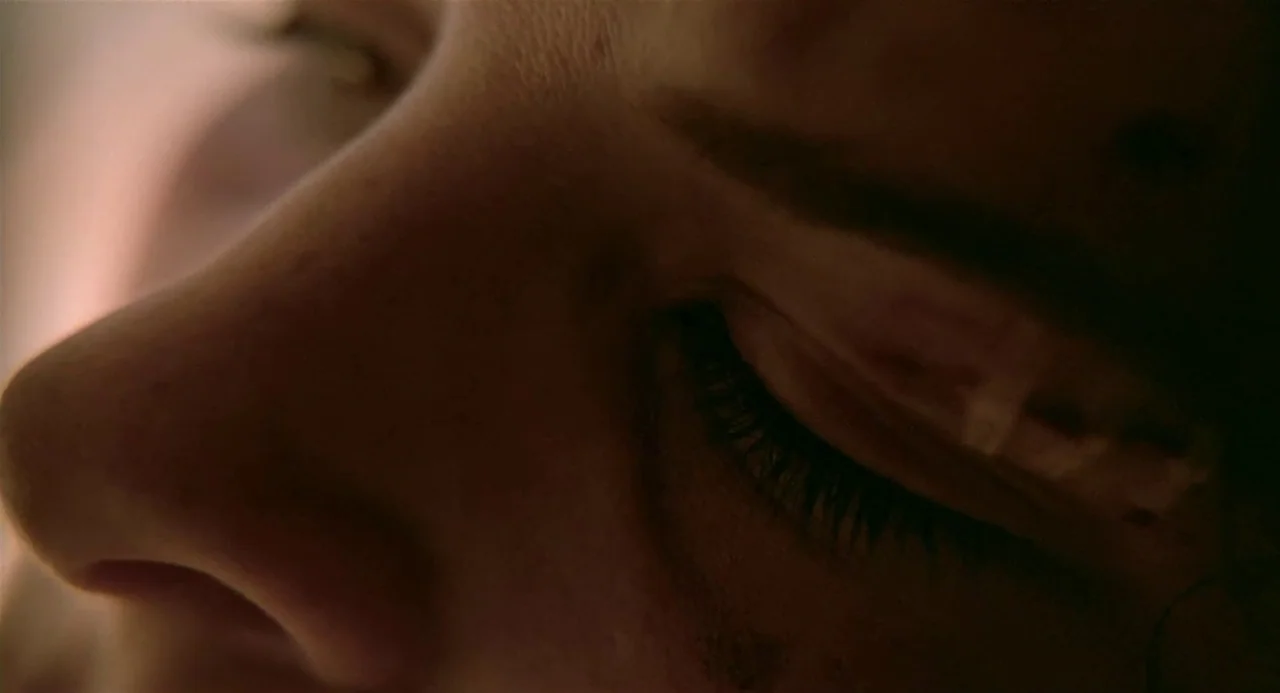 Three Colours: Blue (1993) movie still: closeup — Extreme close-up shot of an individual's eye area in a darkened environment. The subject rests…