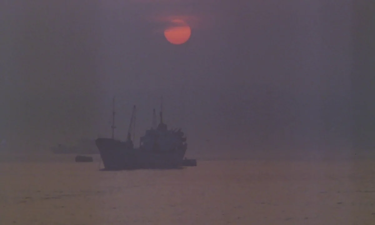 Vampyros Lesbos (1971) movie still: establishing — A dark cargo ship sits on a hazy sea under a dim, red setting sun. The atmosphere is dense with…