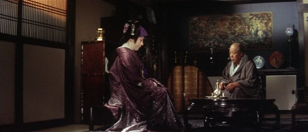 An Actor’s Revenge (1963) movie still: medium — A dimly lit room features traditional Japanese sliding doors and dark wood furniture. A woman in a…