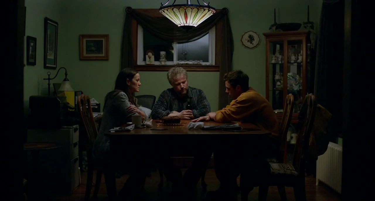 Manchester By The Sea (2016) movie still: medium — A residential dining room features green walls, dark wooden furniture, and a central…