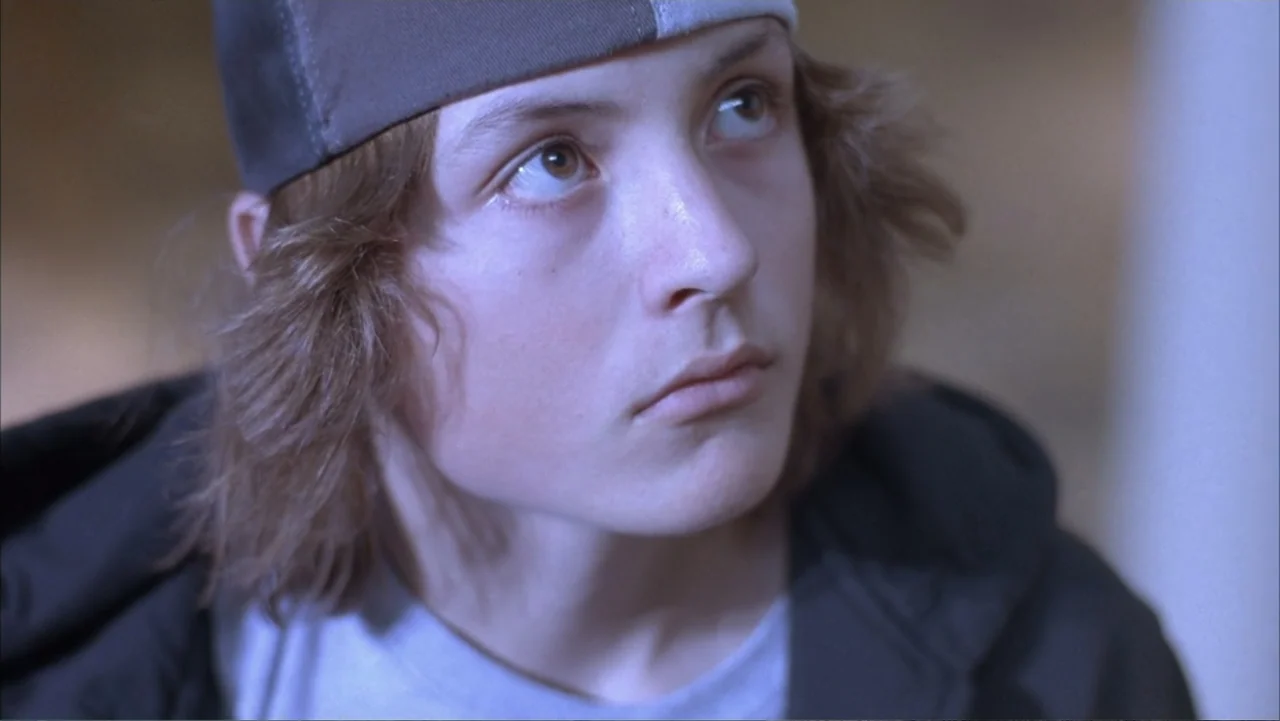 Paranoid Park (2007) movie still: closeup — A close-up shot focuses on a young person in a neutral interior space. The subject gazes upward with a…