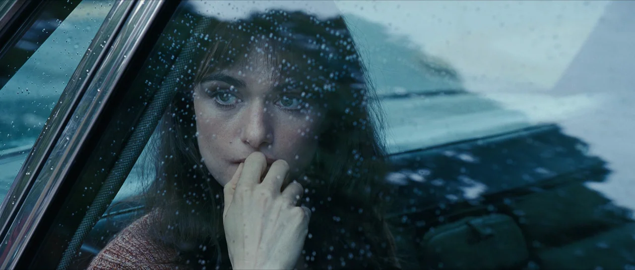 The Lovely Bones (2009) movie still: closeup — The interior of a vehicle displays a rain-spattered side window during a grey day. A woman sits in…