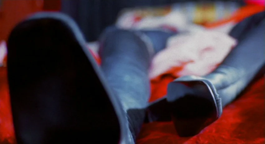 A Lizard In A Woman’s Skin (1971) movie still: closeup — A close-up shot of black material resting on a textured red surface. The fabric is draped…