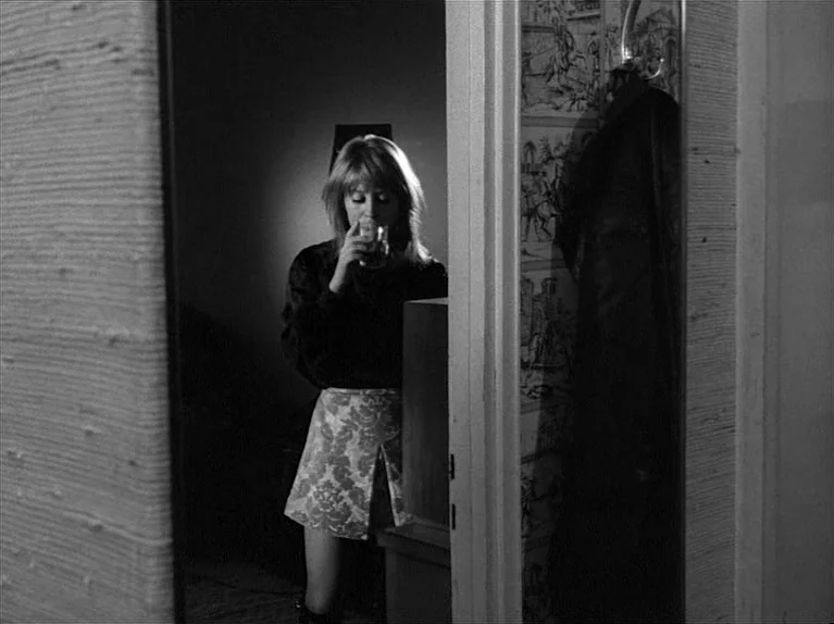 Gods Of The Plague (1970) movie still: medium — A dimly lit narrow space features patterned wallpaper and a doorway leading to a room. A woman…