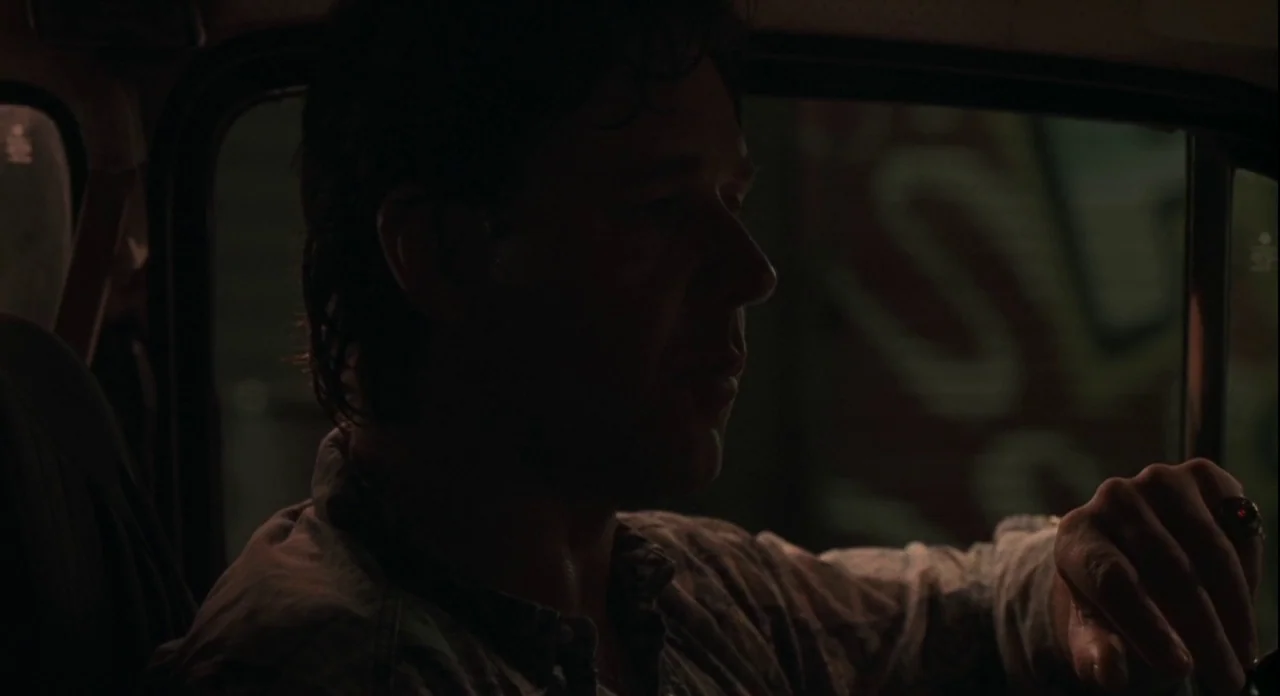 American Gangster (2007) movie still: medium — The interior of a car at night showing dark shapes and minimal urban exterior light. A man in a…