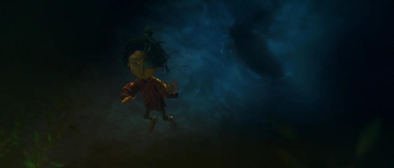 Kubo and the Two Strings movie still: fullbody — A small figure drifts through murky deep blue water with faint light from above. The figure hangs…