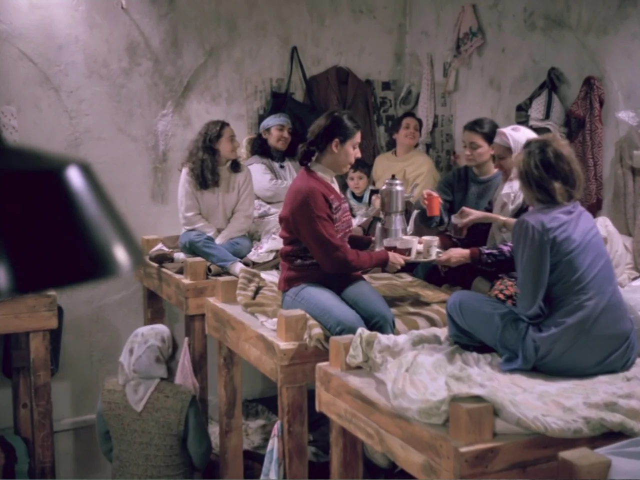 Don't Let Them Shoot the Kite (1989) movie still: medium — A confined dormitory space with raw concrete walls and multiple wooden bunk beds. Several…