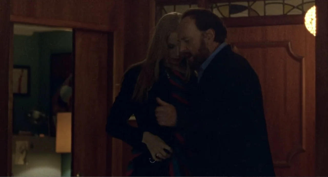Forty Shades of Blue (2005) movie still: medium — A dark, wood-paneled hallway with a glimpse into a secondary room featuring green walls. A man and…