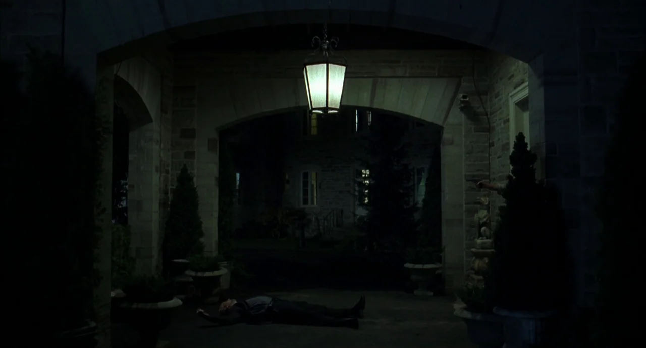 A History of Violence (2005) movie still: wide — A stone-paved courtyard with arched entryways features potted evergreens flanking the central path.…