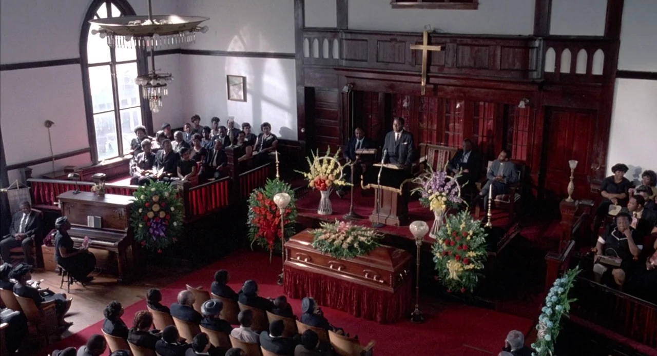 Mississippi Burning (1988) movie still: wide — A church interior with dark wood paneling, a wooden cross, and red carpeted flooring. A congregation…
